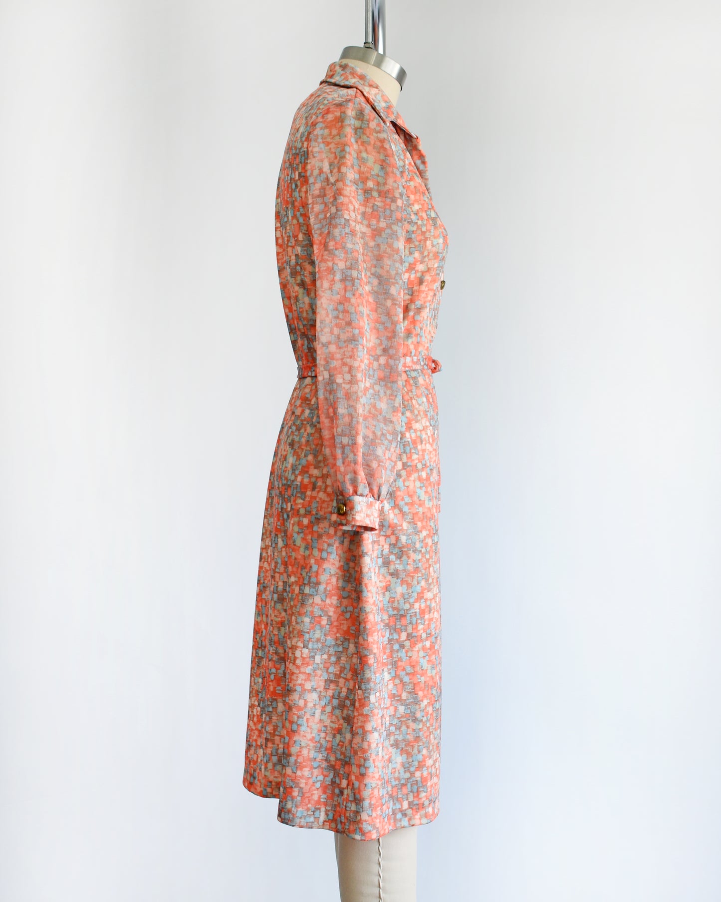 side view of a vintage 1970s orange and blue dress on a mannequin against a white background