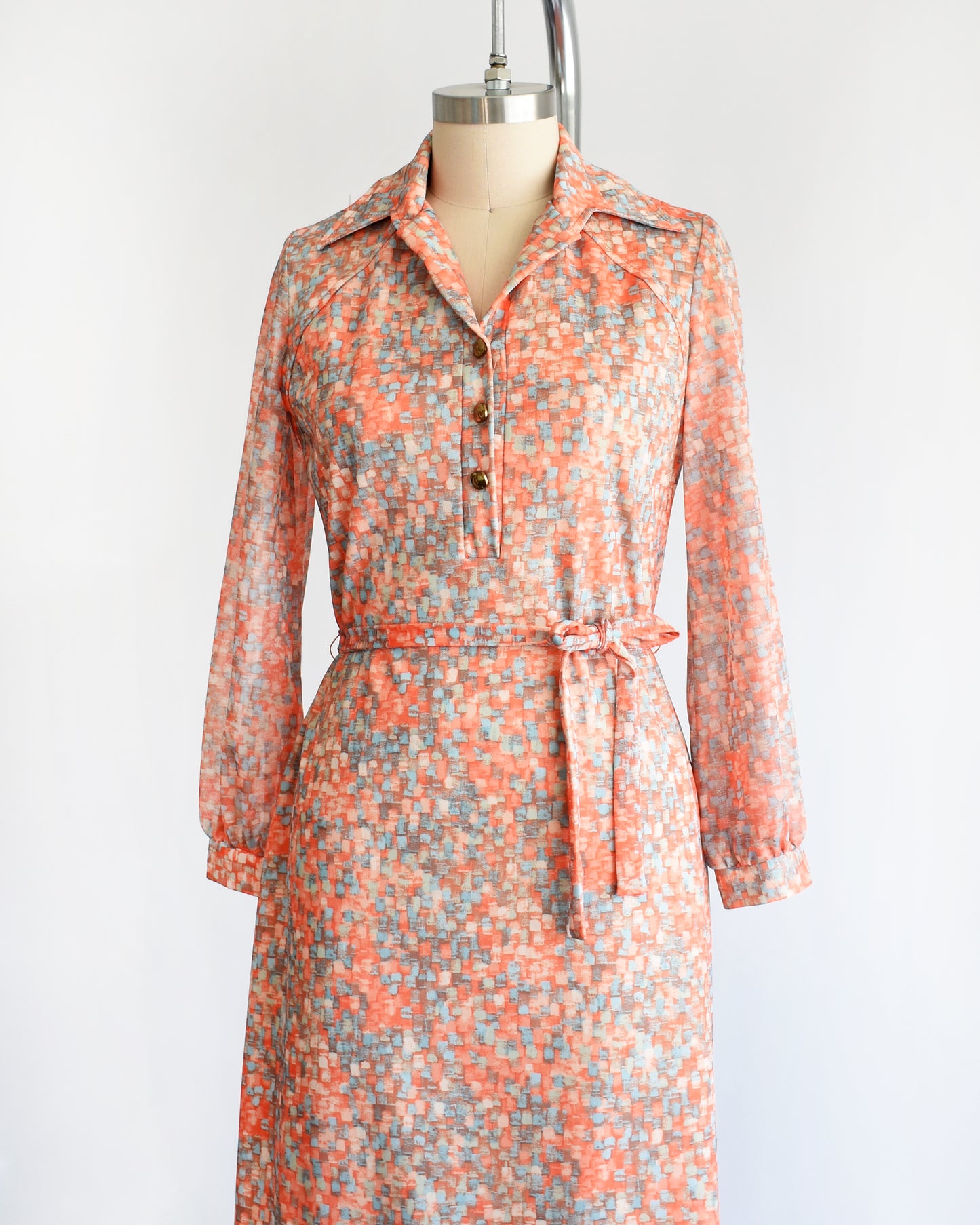 side front view of a vintage 1970s orange and blue dress on a mannequin against a white background
