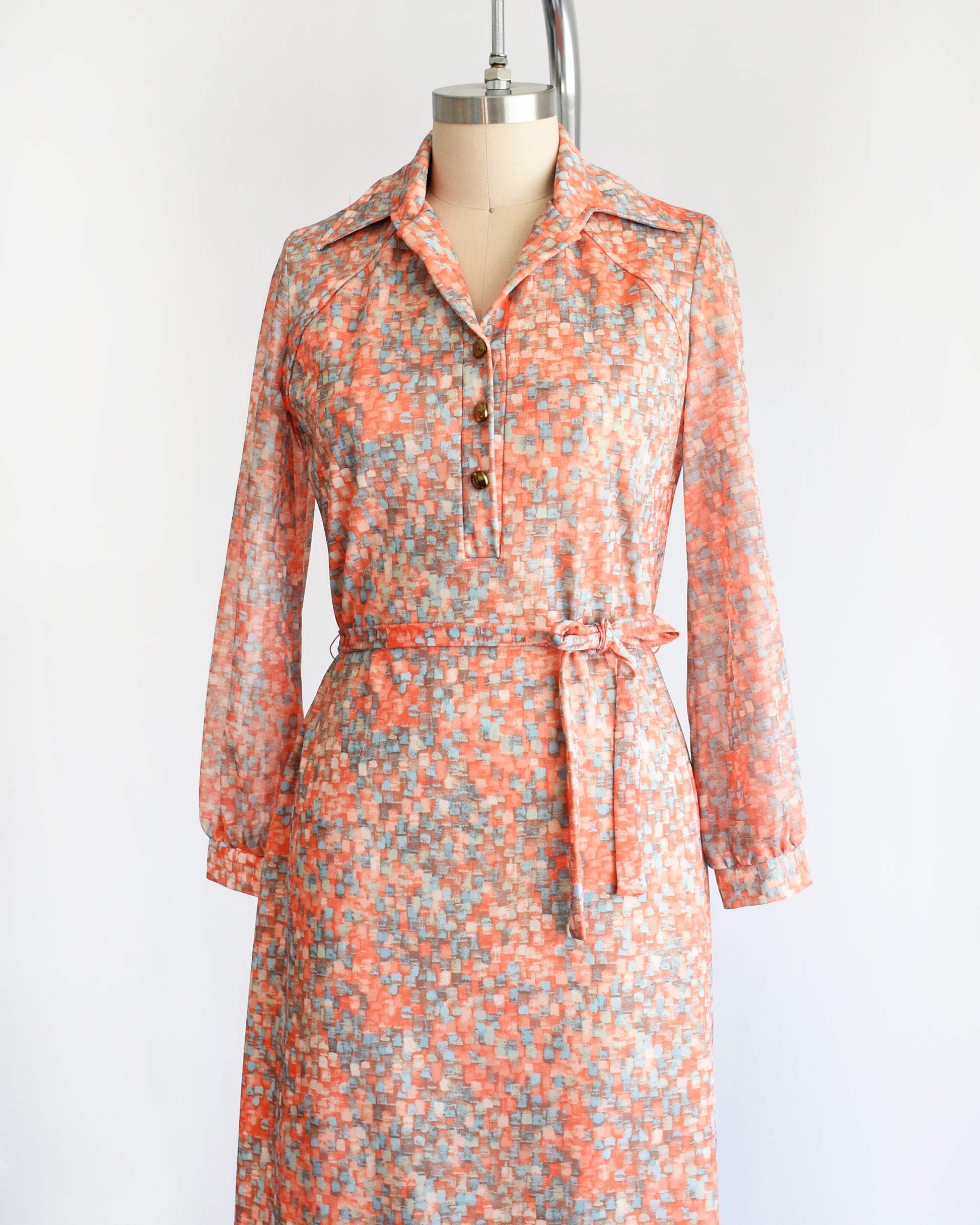side front view of a vintage 1970s orange and blue dress on a mannequin against a white background