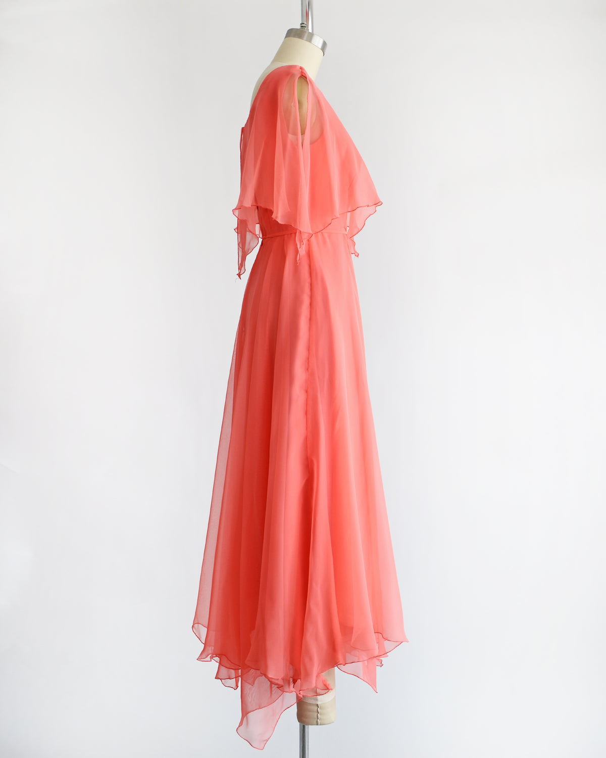 side view of a vintage 1970s coral flutter dress on a mannequin against a white background
