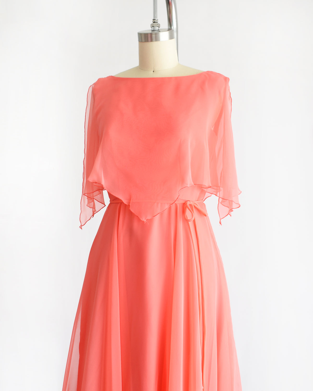 side front view of a vintage 1970s coral flutter dress on a mannequin against a white background