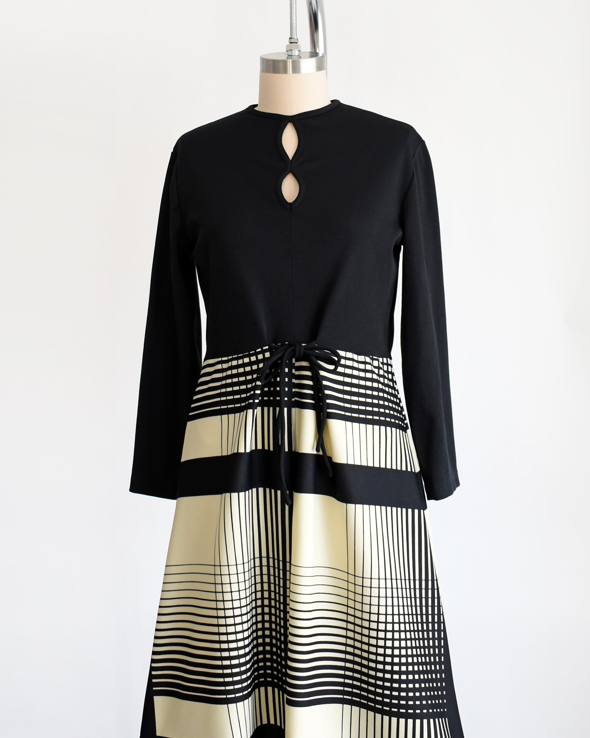 side front view of a vintage 1970s black and cream striped dress that has two keyhole cutouts on the front of the bodice.