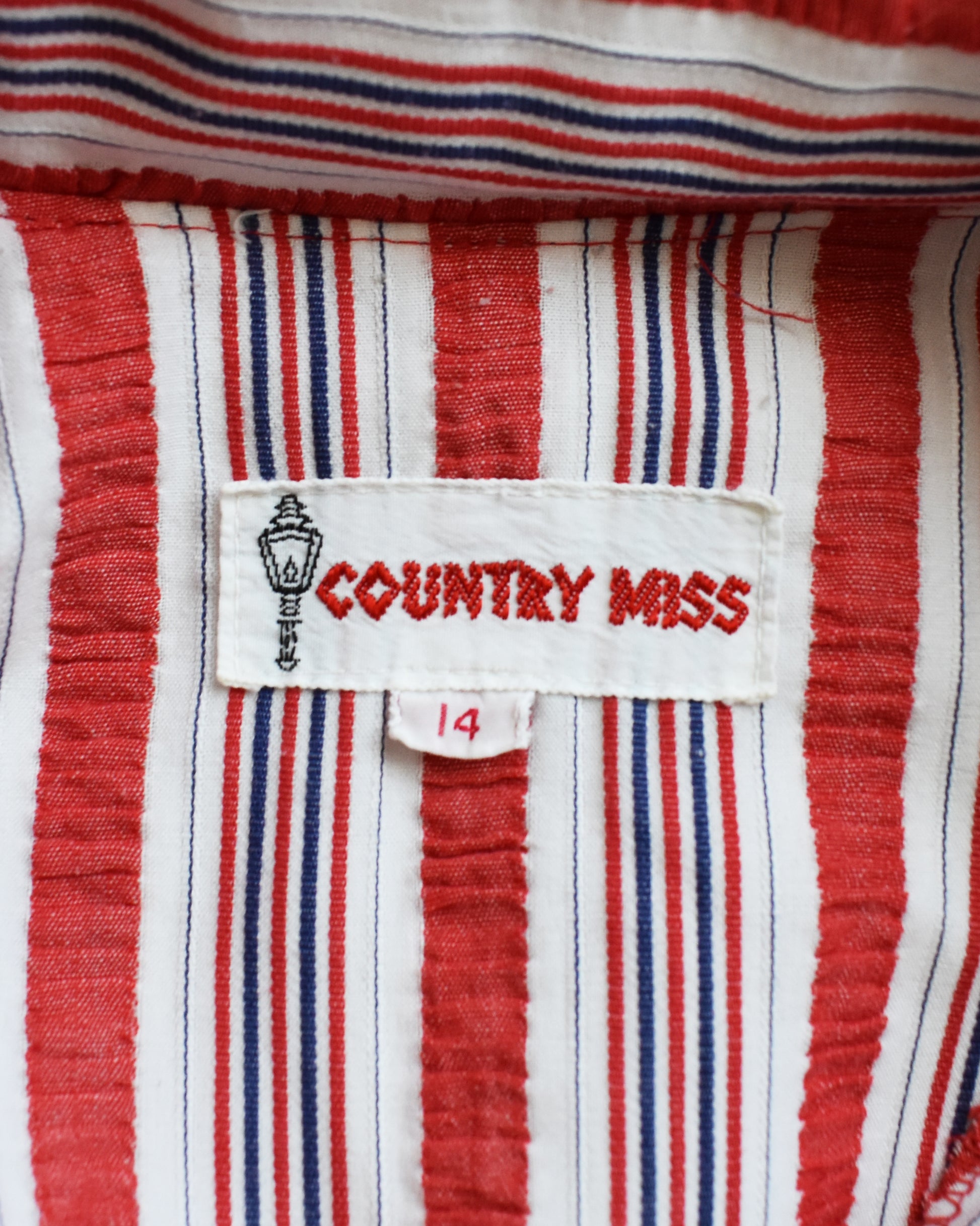 Close-up of a red, white, and blue striped fabric with 'Country Miss' label.
