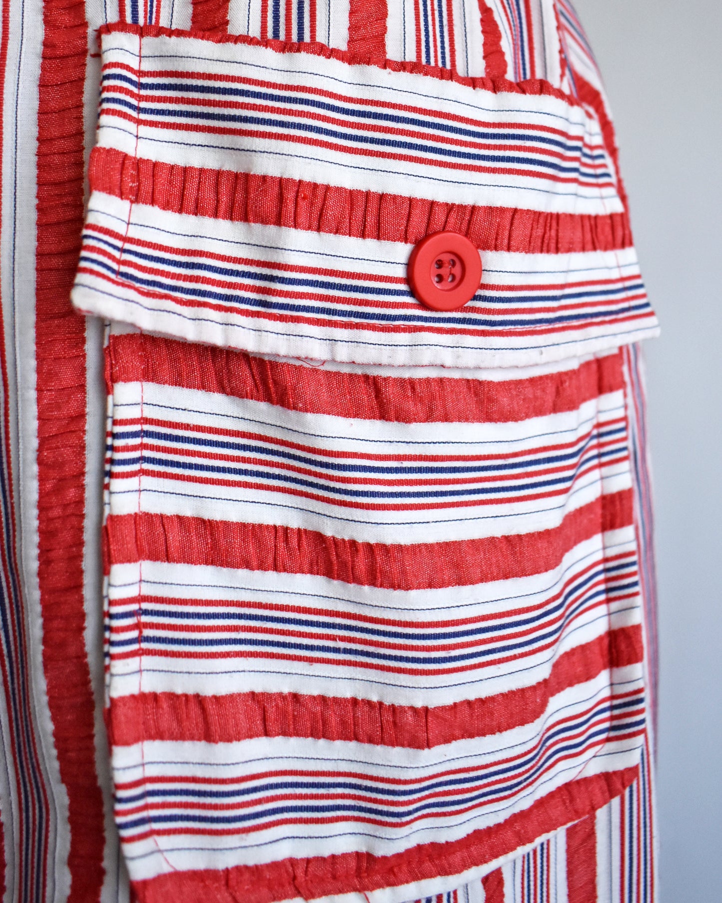 close up of the pocket on a vintage 1970s red and white striped dress on a mannequin against a white background