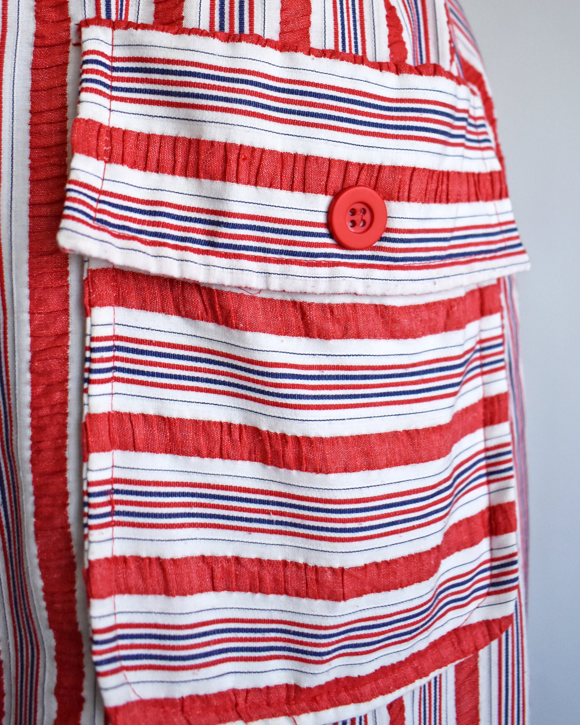 close up of the pocket on a vintage 1970s red and white striped dress on a mannequin against a white background