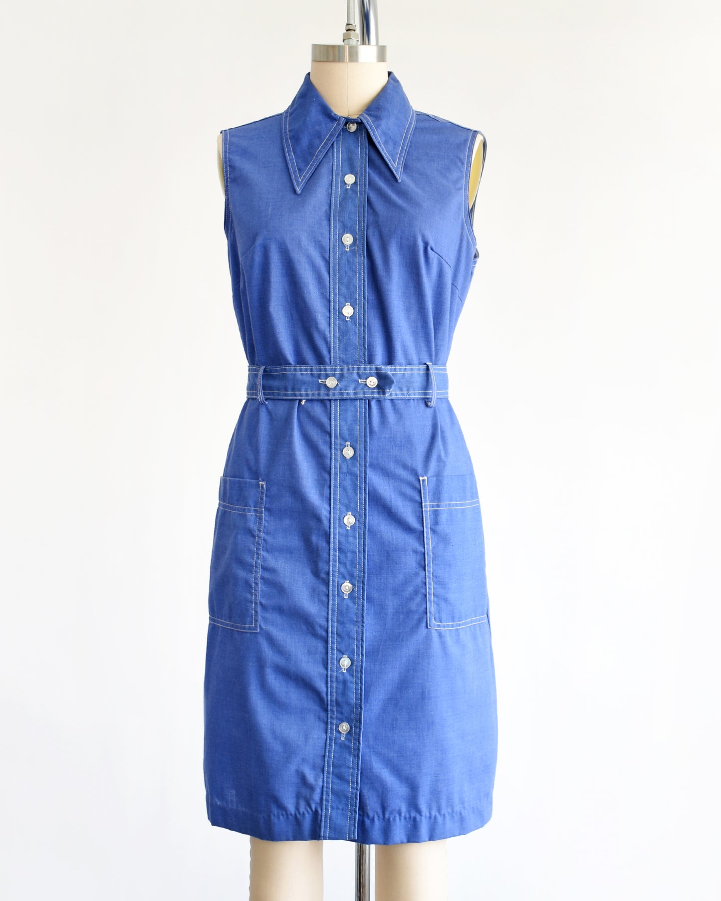a vintage 1970s blue dress on a mannequin against a white background