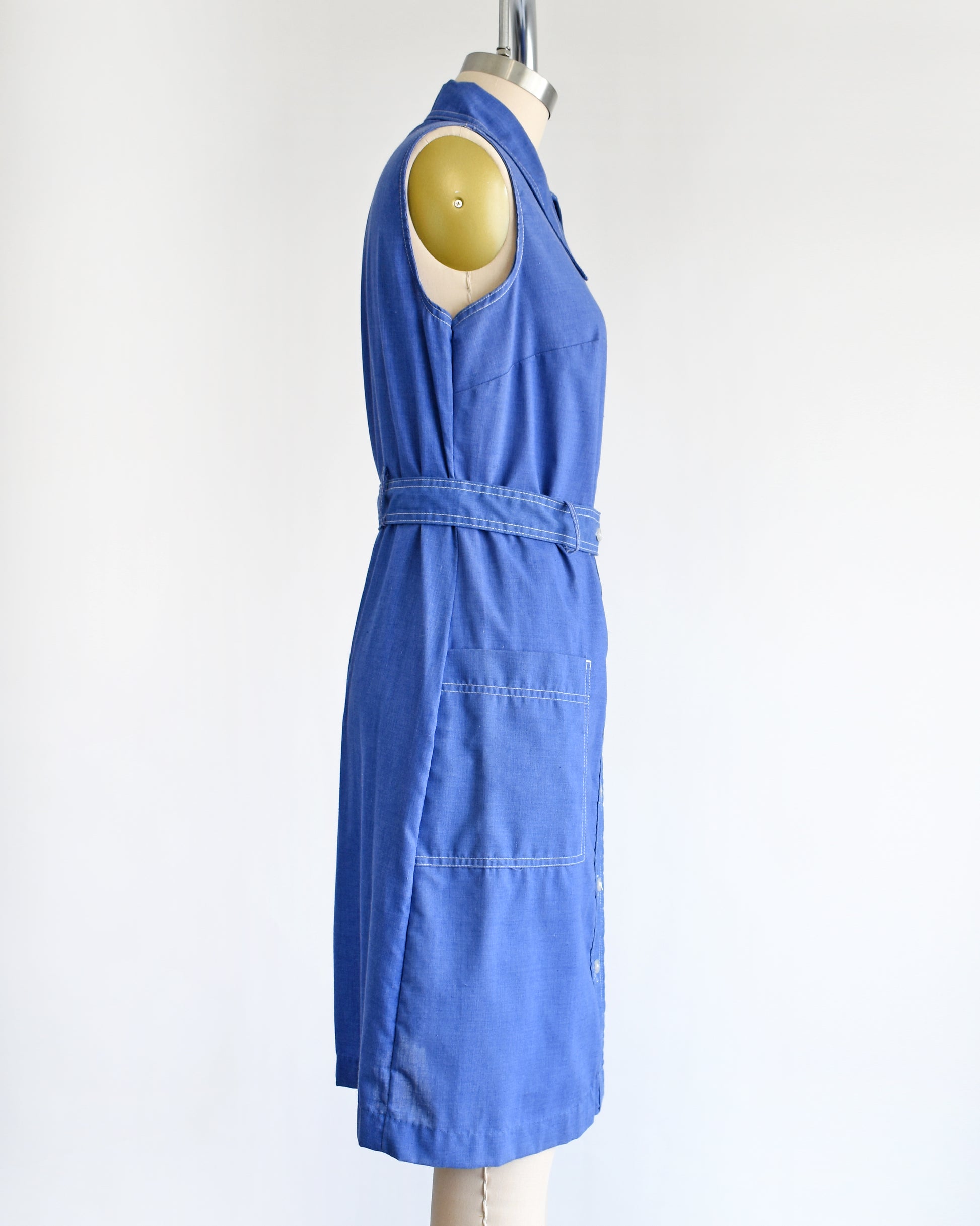 side view of a vintage 1970s blue dress on a mannequin against a white background
