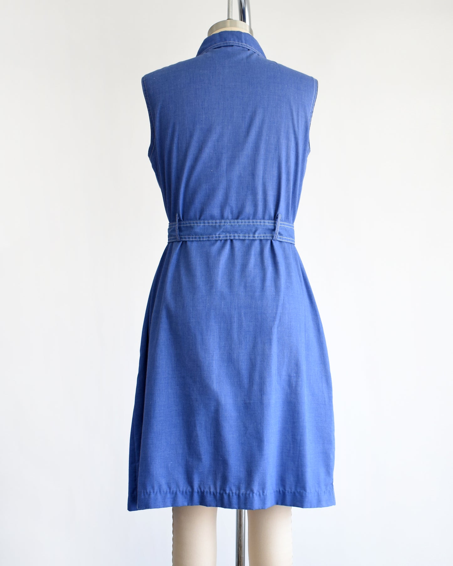 back view of a vintage 1970s blue dress on a mannequin against a white background