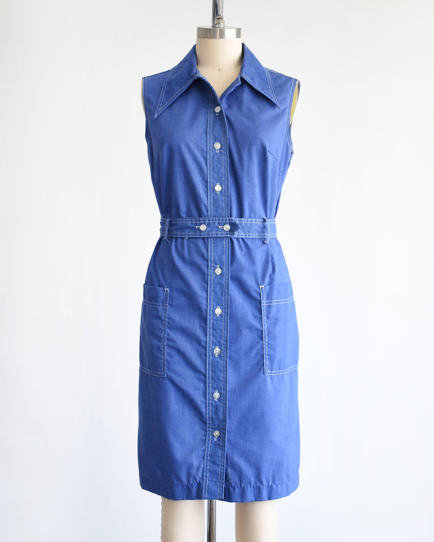 a vintage 1970s blue dress on a mannequin against a white background