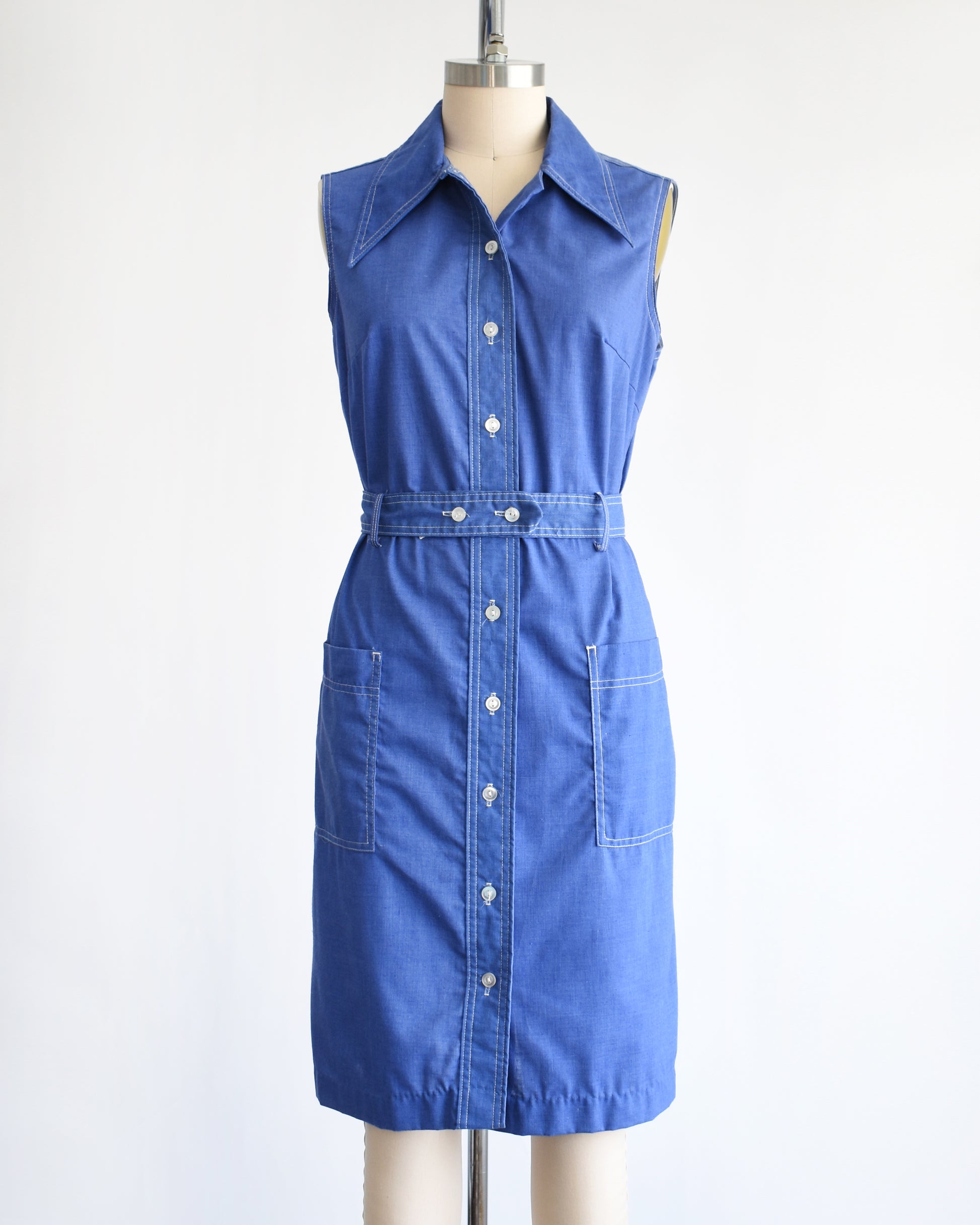 a vintage 1970s blue dress on a mannequin against a white background