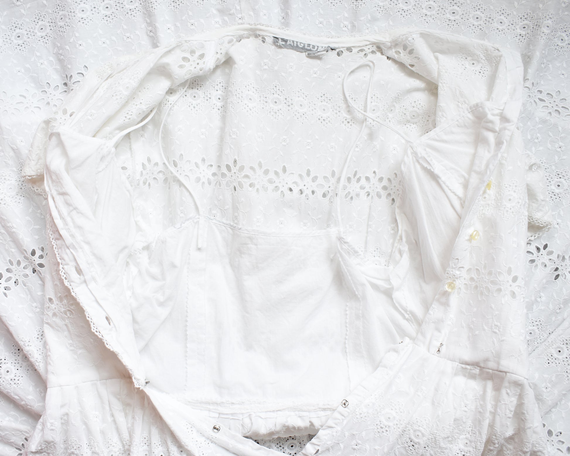 close up of the bodice of a vintage 1960s L’Aiglon eyelet white dress which is open and shows the lined bodie