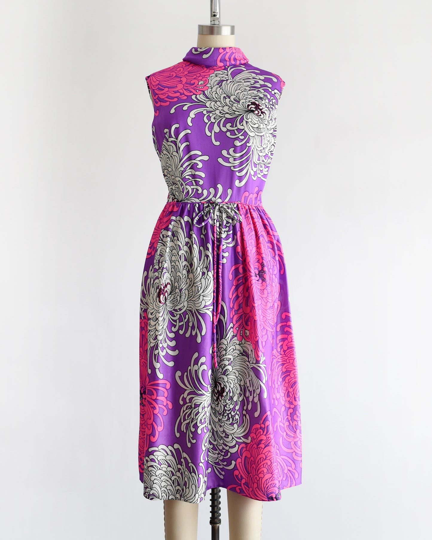 a vintage 1970s purple dress with floral patterns on a mannequin against a white background