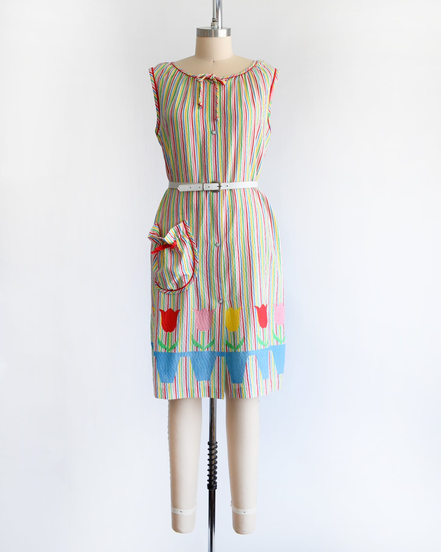 a vintage 1970s rainbow striped house dress with tulips around the hem on a mannequin against a white background