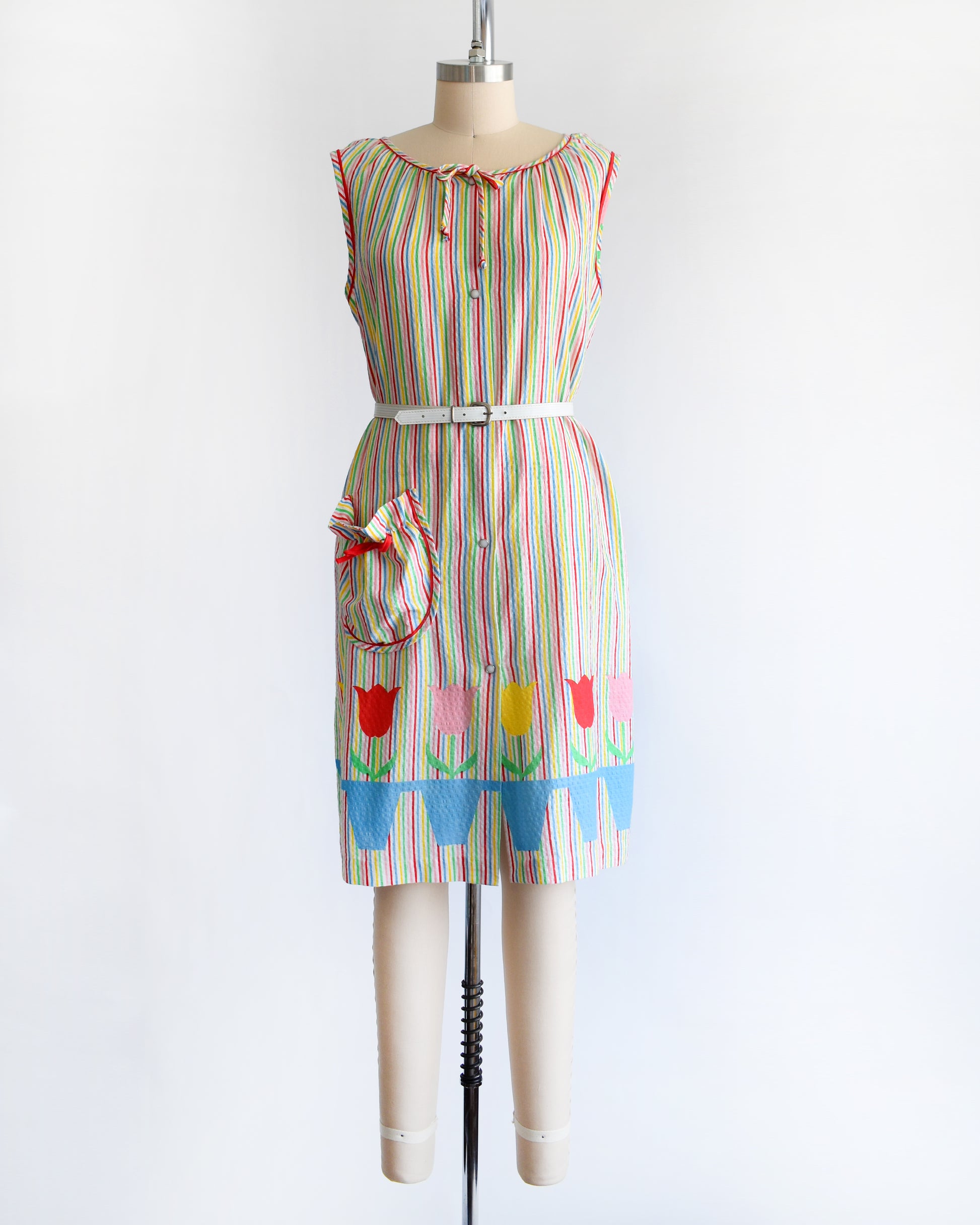 a vintage 1970s rainbow striped house dress with tulips around the hem on a mannequin against a white background