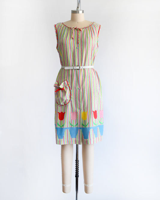 a vintage 1970s rainbow striped house dress with tulips around the hem on a mannequin against a white background