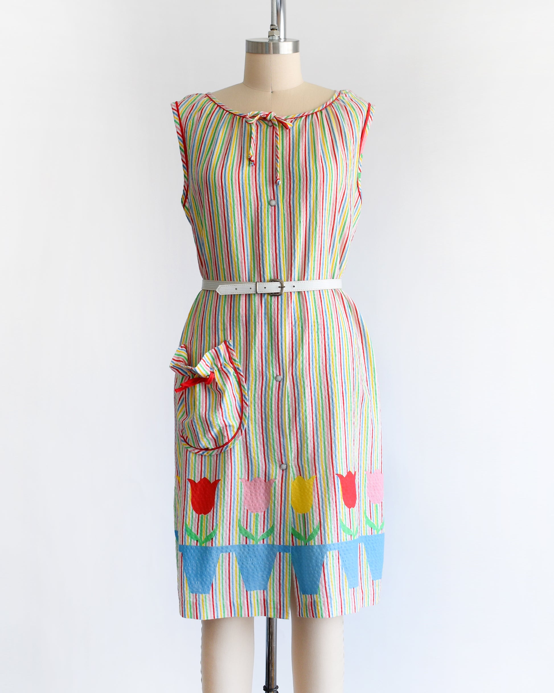 a vintage 1970s rainbow striped house dress with tulips around the hem on a mannequin against a white background