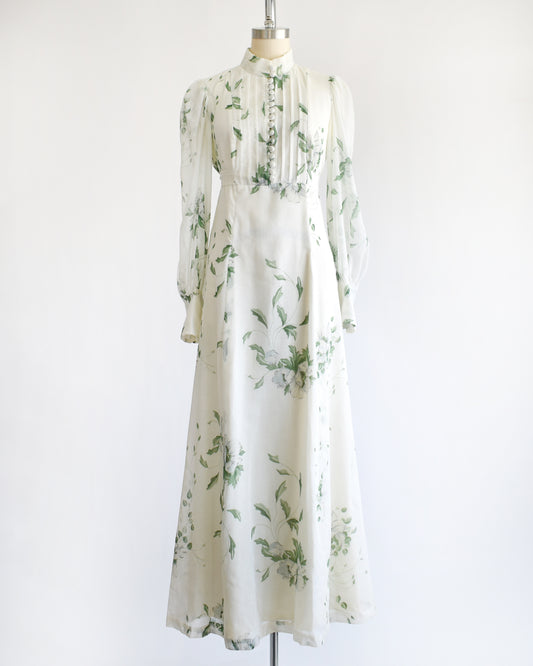 a vintage 1970s white dress with green floral pattern on a mannequin against a white background