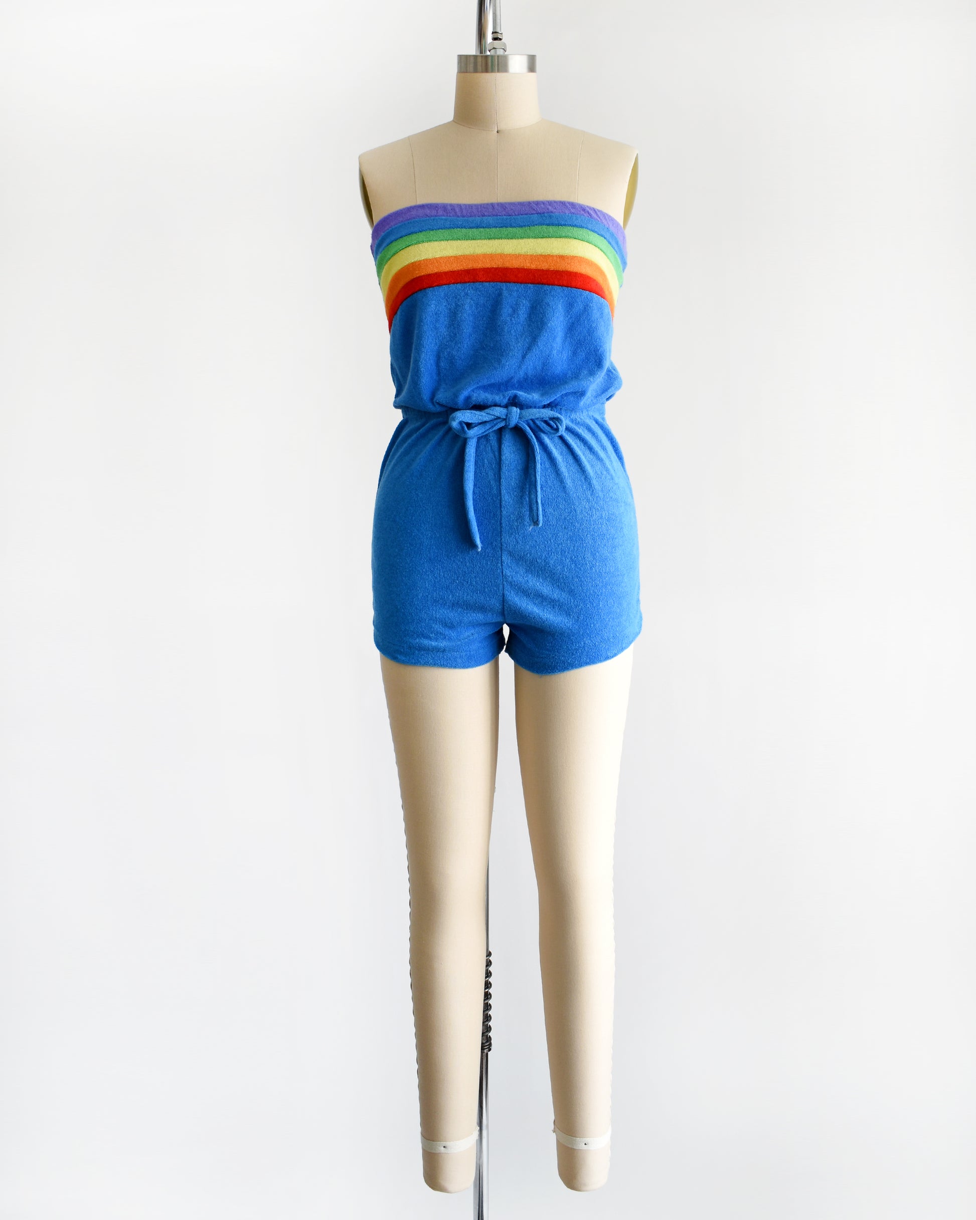 a vintage late 1970s early 1980s blue terry cloth romper that has a rainbow stripe on the top 