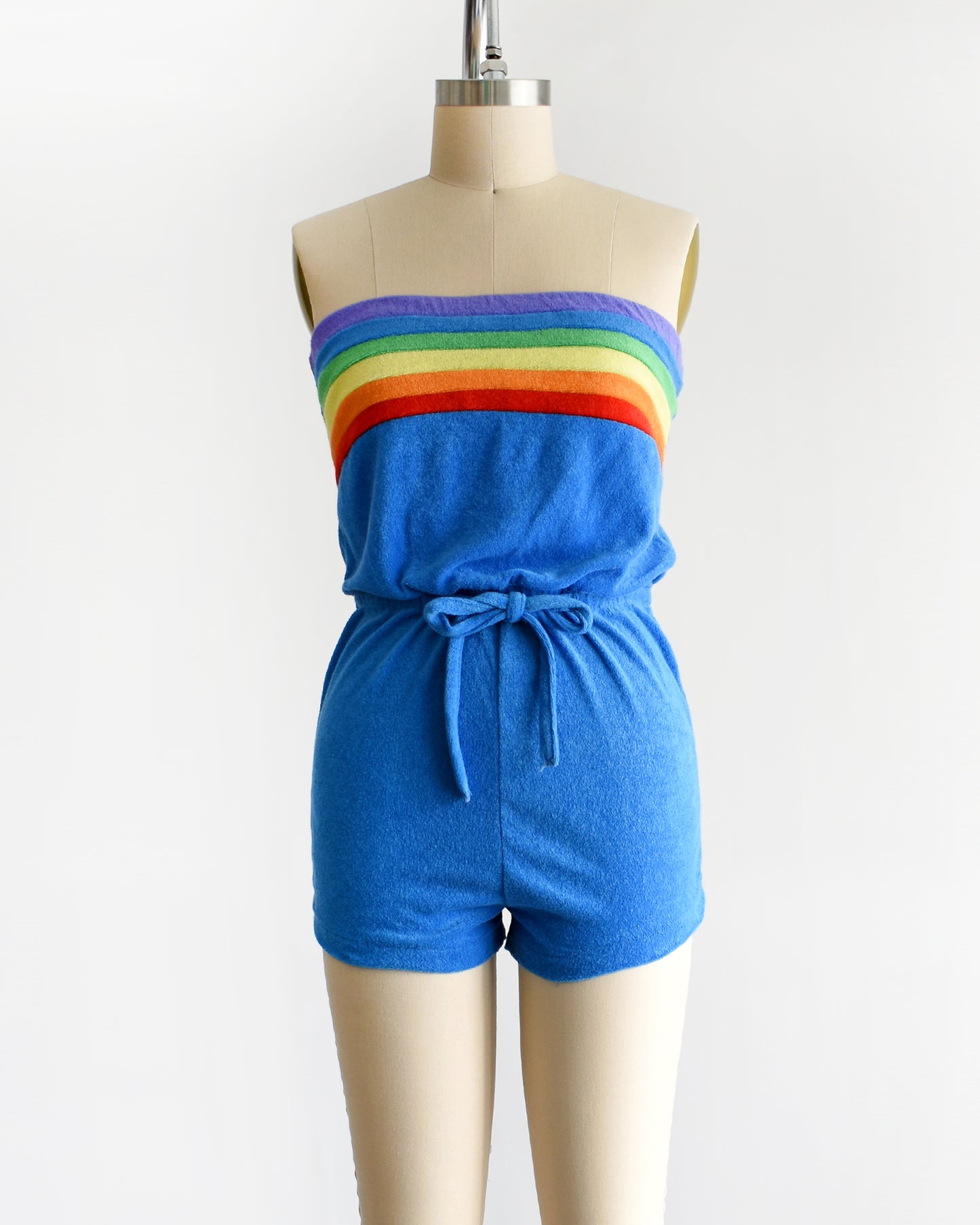 a vintage late 1970s early 1980s blue terry cloth romper that has a rainbow stripe on the top 