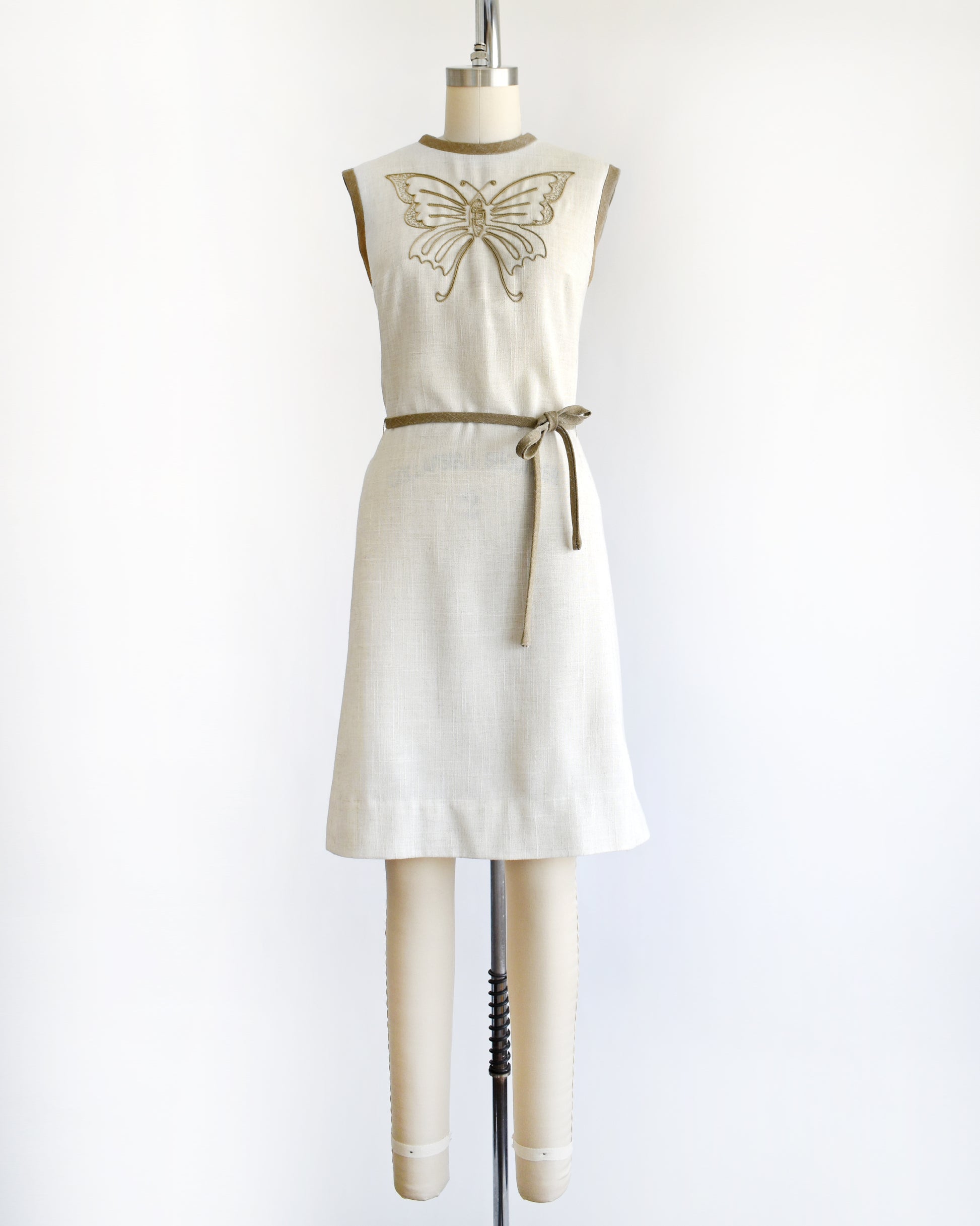 A vintage 1970s dress with butterfly design on a mannequin against a white background