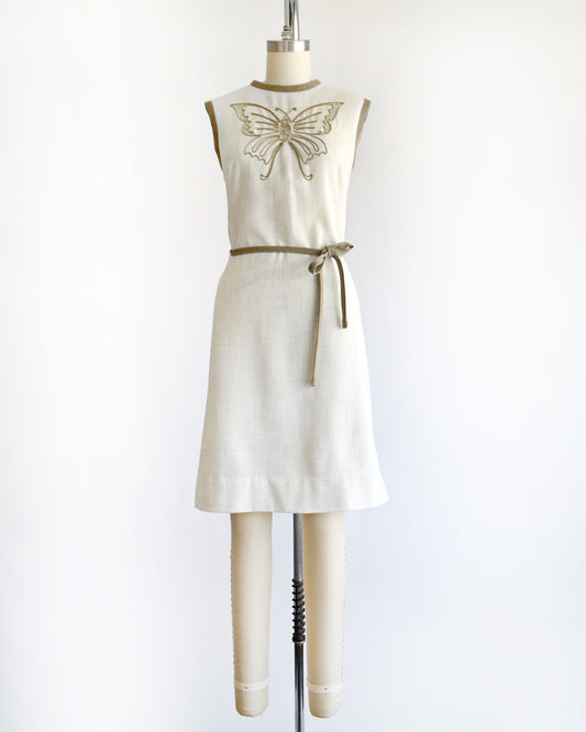 A vintage 1970s dress with butterfly design on a mannequin against a white background