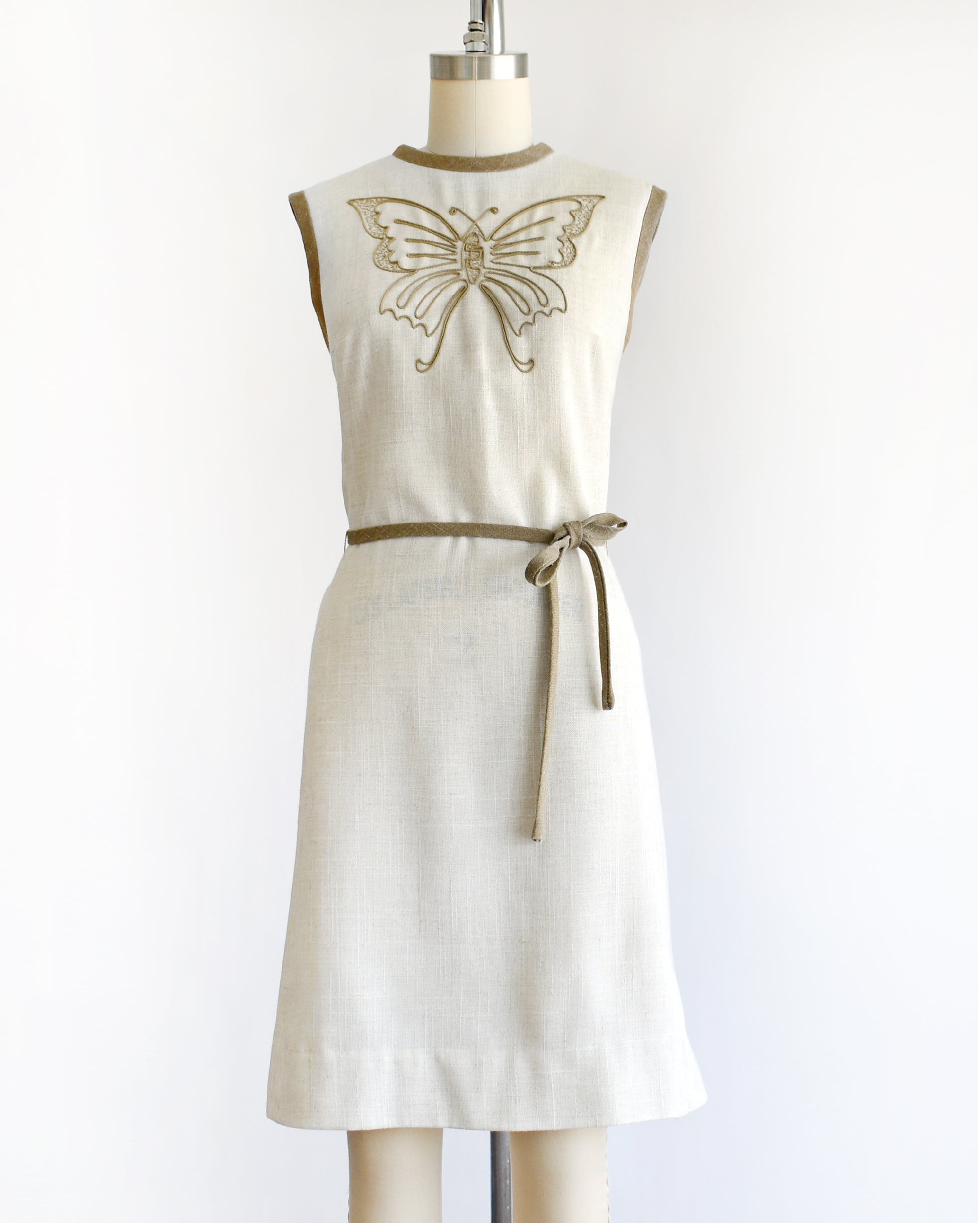 A vintage 1970s dress with butterfly design on a mannequin against a white background