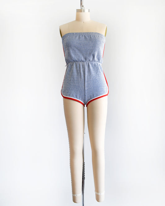 a vintage 1970s blue and white striped romper with red and white trim on the sides and legs.