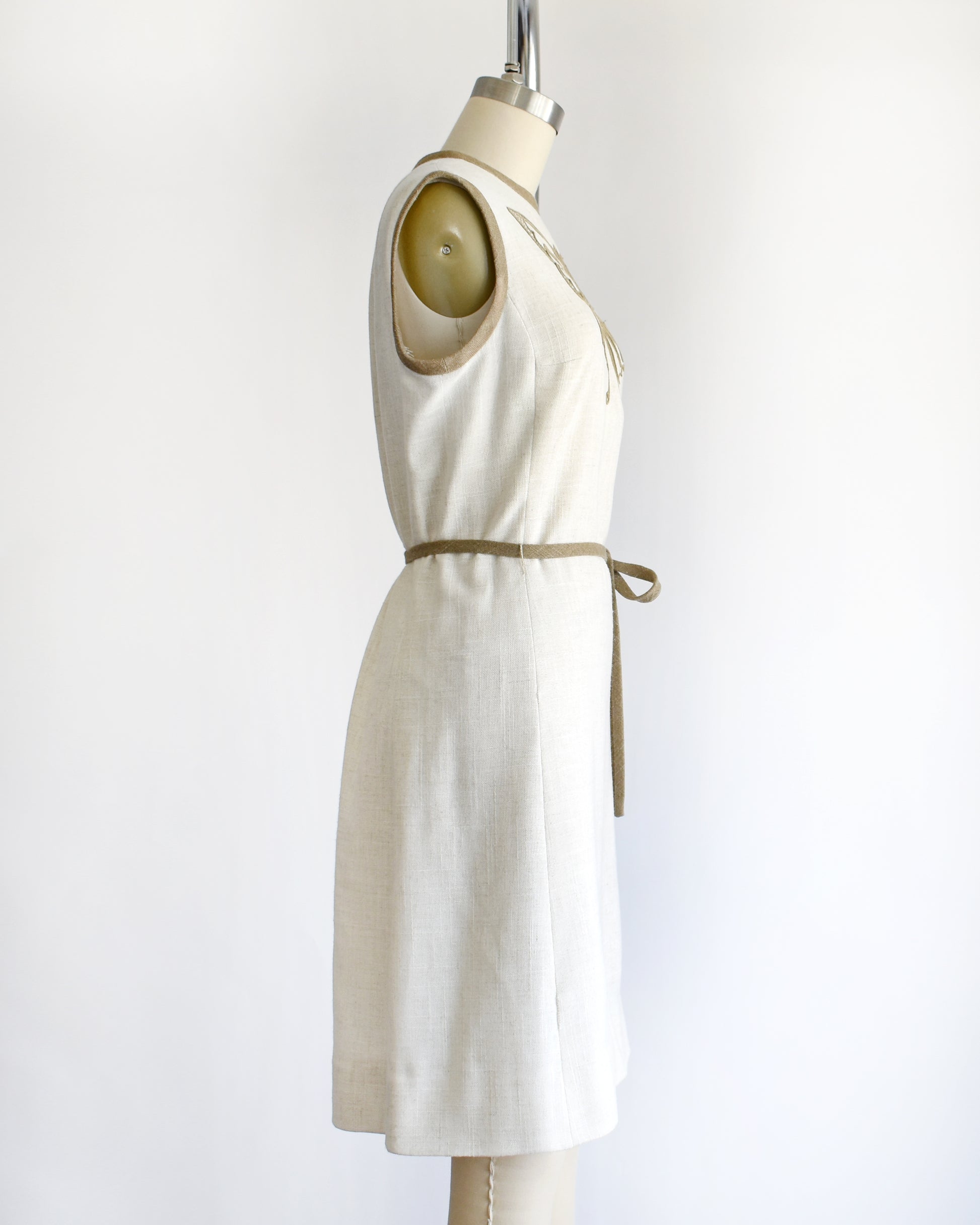 side view of a vintage 1970s dress with butterfly design on a mannequin against a white background