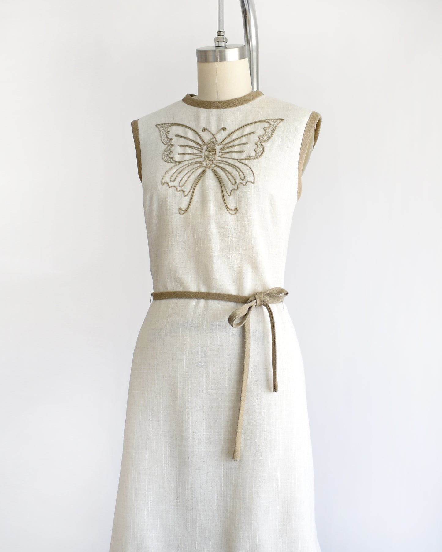 side front view of a vintage 1970s dress with butterfly design on a mannequin against a white background
