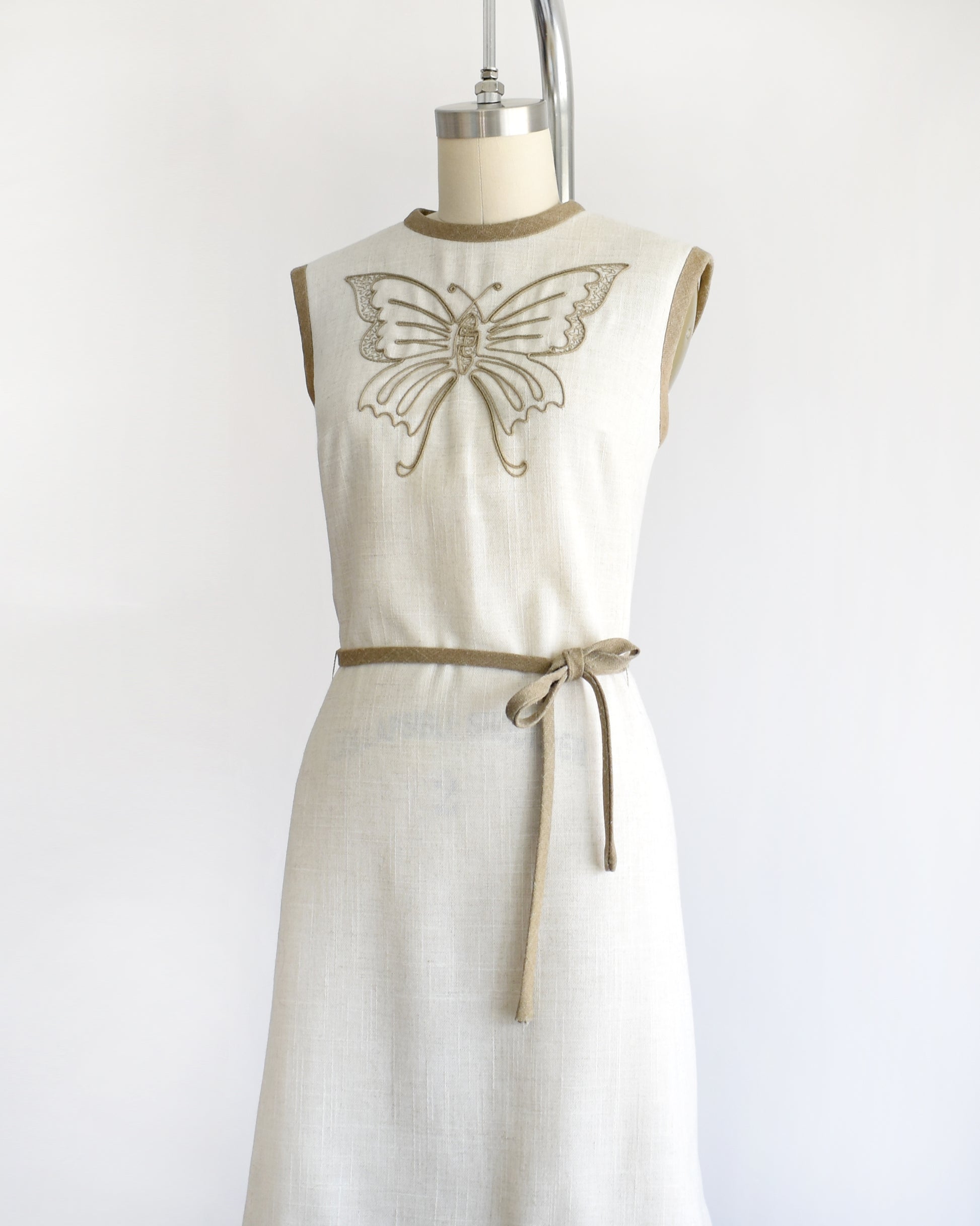 side front view of a vintage 1970s dress with butterfly design on a mannequin against a white background