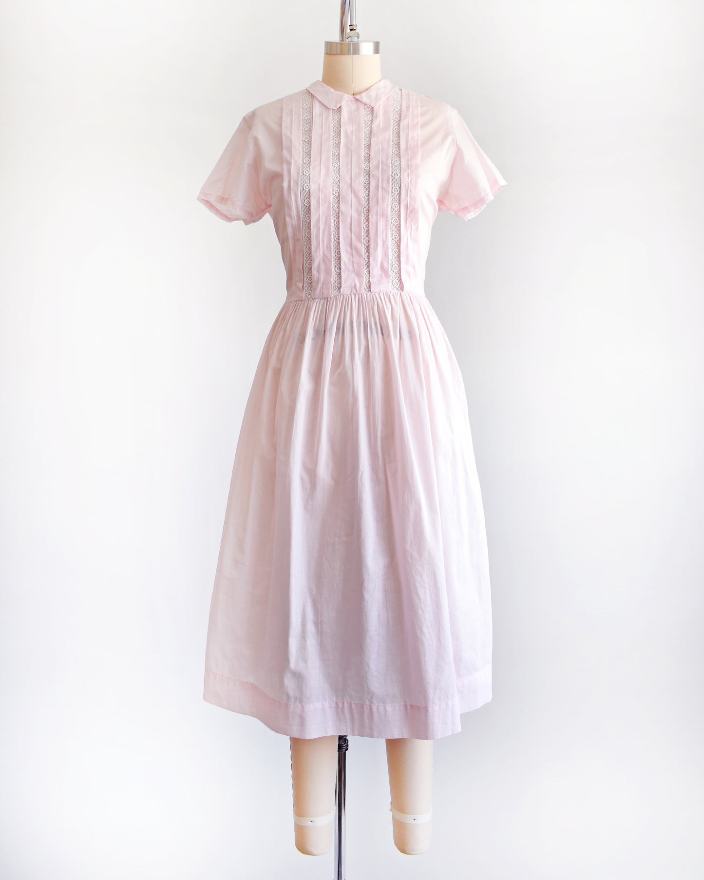 a vintage 1950s pink dress on a mannequin against a white background