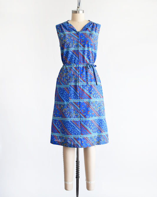 a vintage 1970s blue floral dress on a mannequin against a white background