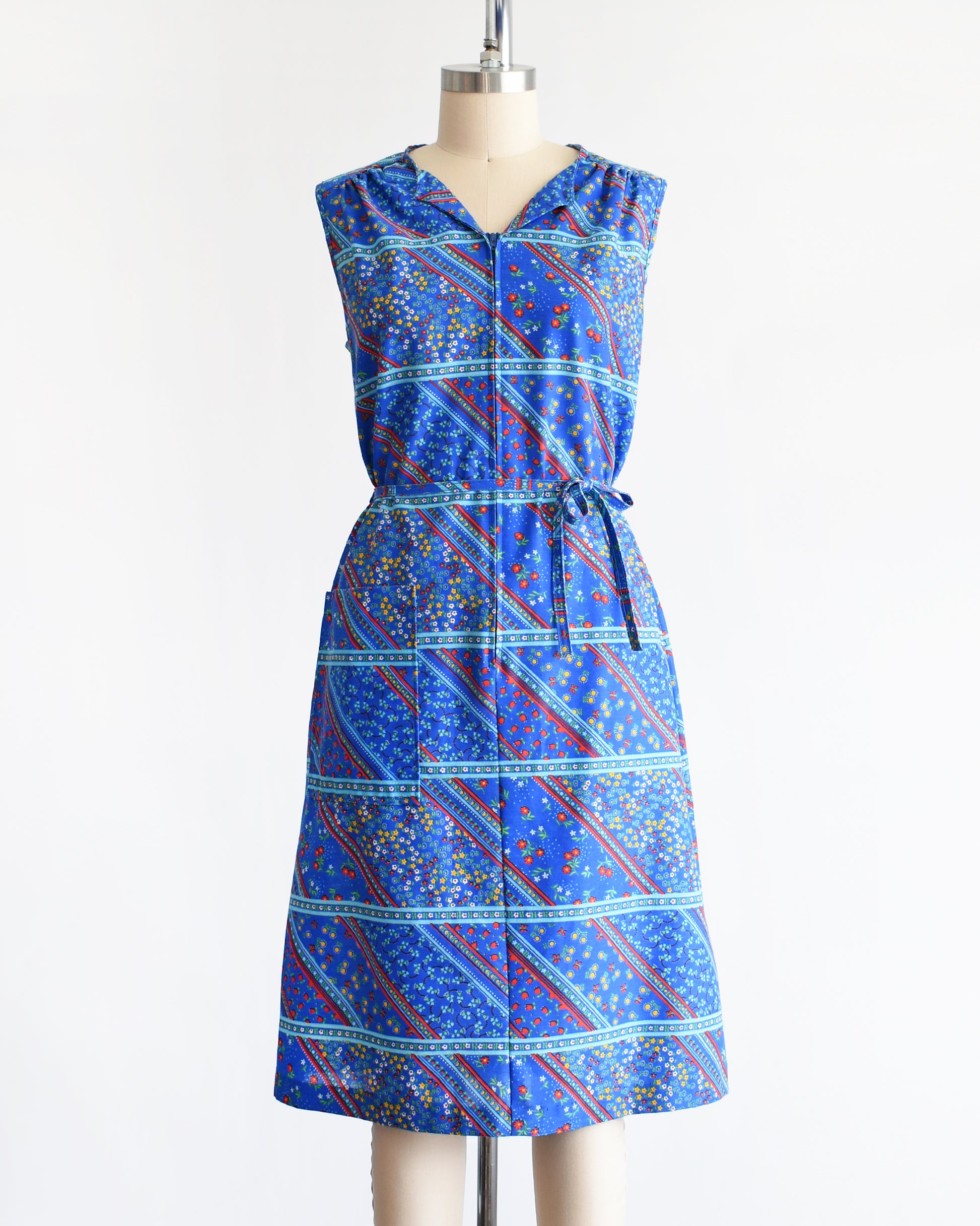 a vintage 1970s blue floral dress on a mannequin against a white background