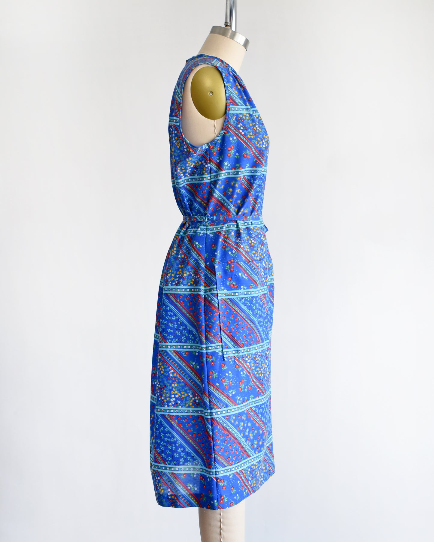side view of a vintage 1970s blue floral dress on a mannequin against a white background