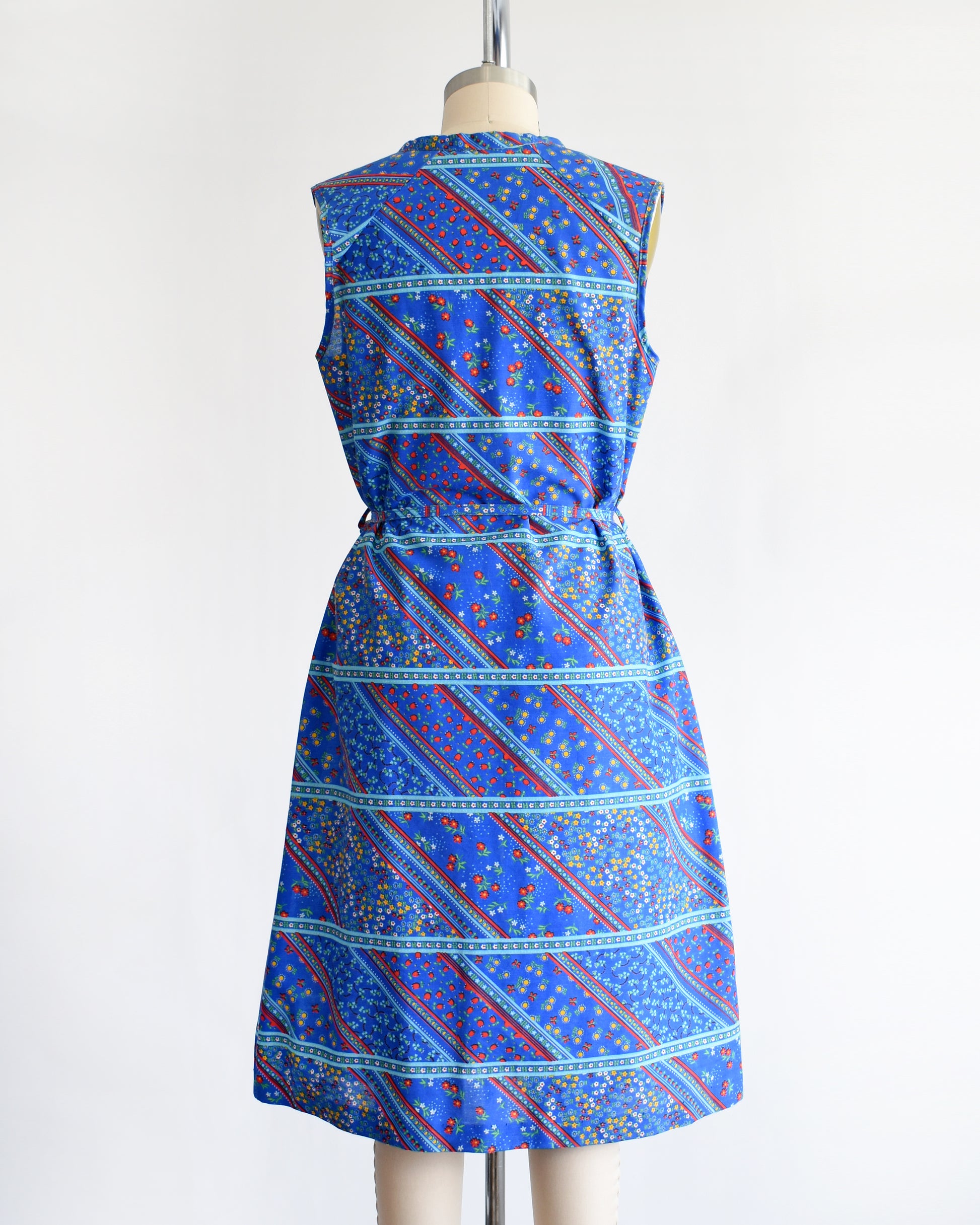 back view of a vintage 1970s blue floral dress on a mannequin against a white background