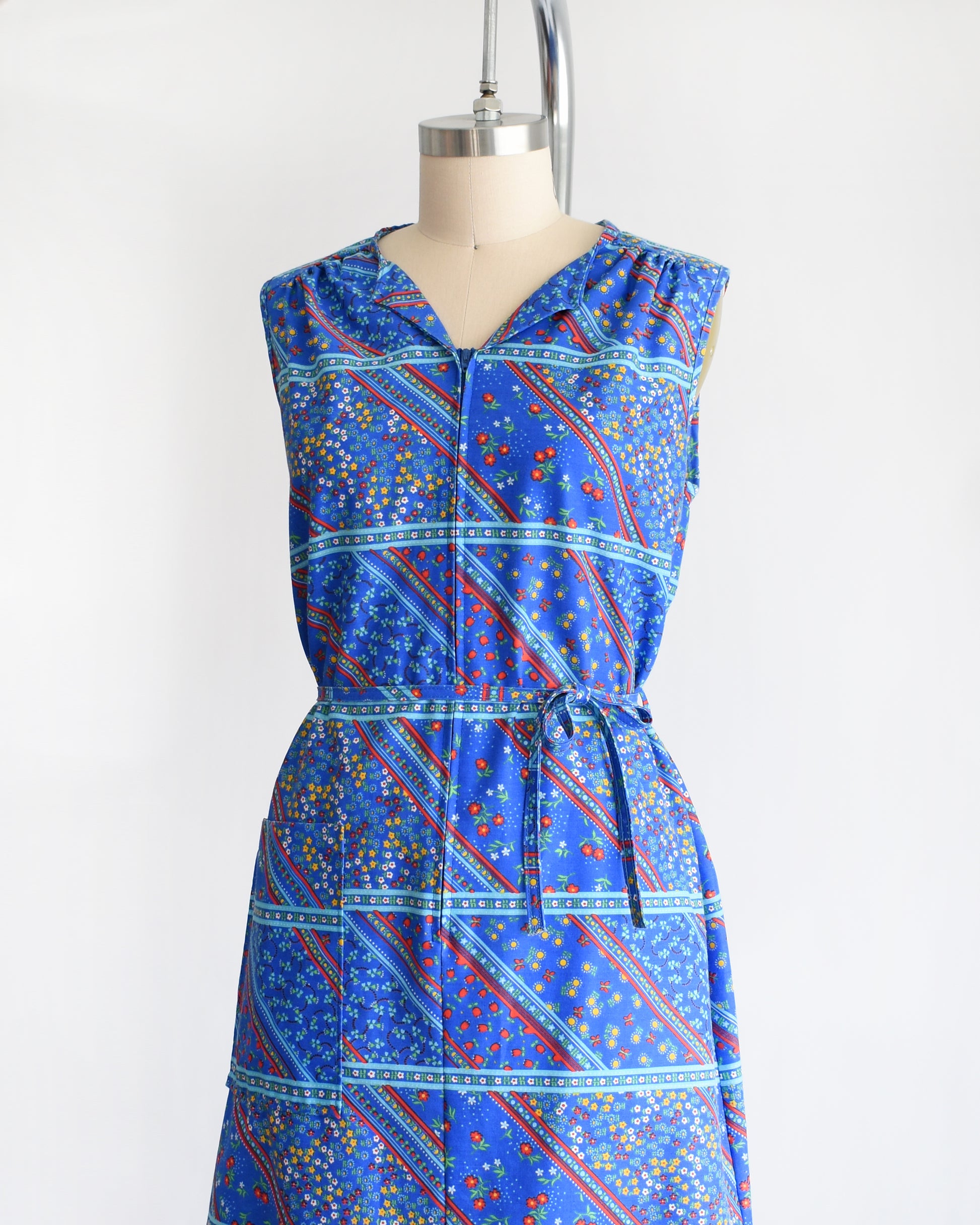 side front view of a vintage 1970s blue floral dress on a mannequin against a white background