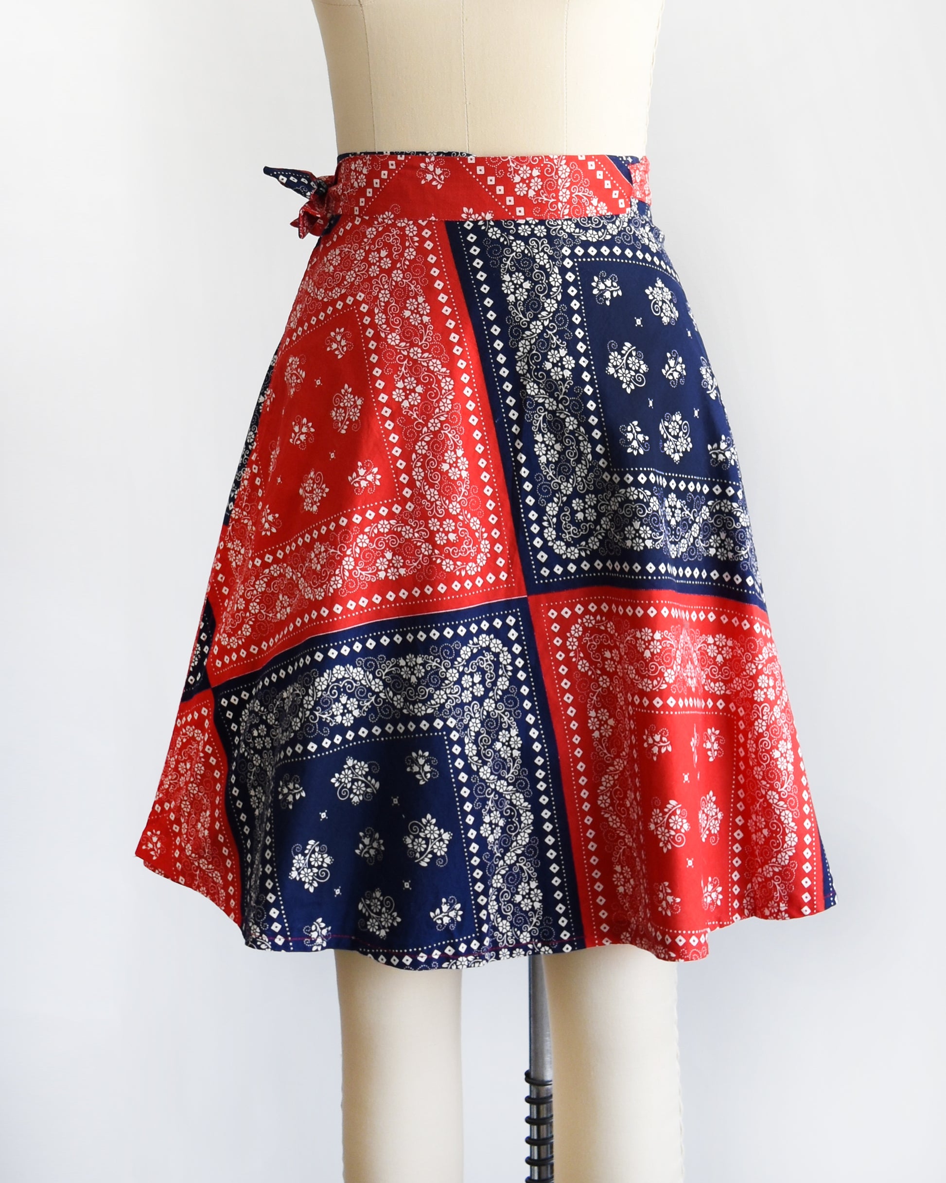 side front view of a vintage 1970s red and blue bandana patterned skirt on a mannequin against a white background