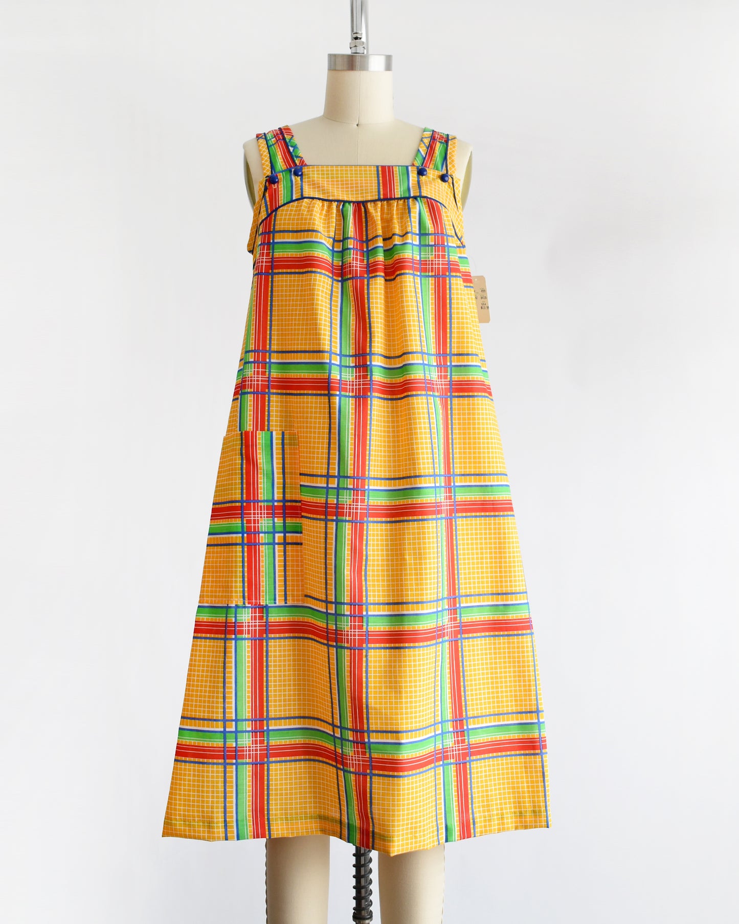 a vintage 1970s yellow plaid dress on a mannequin against a white background