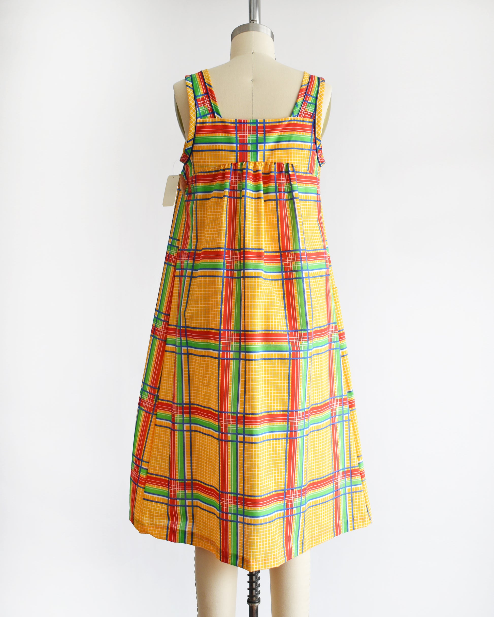 back view of a vintage 1970s yellow plaid dress on a mannequin against a white background