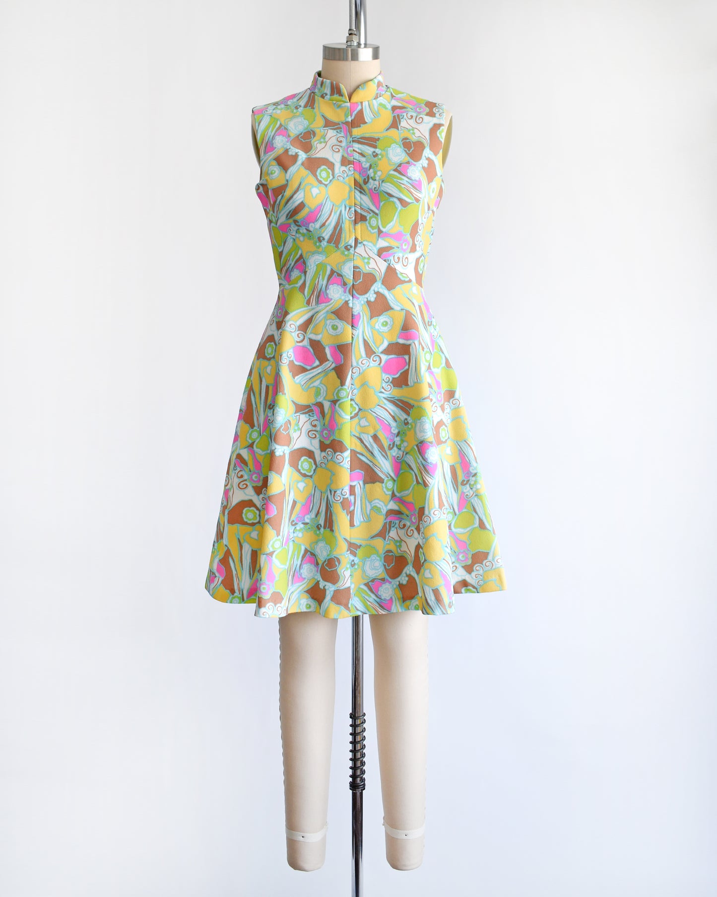 a vintage 1970s mod colorful floral dress on a mannequin against a white background