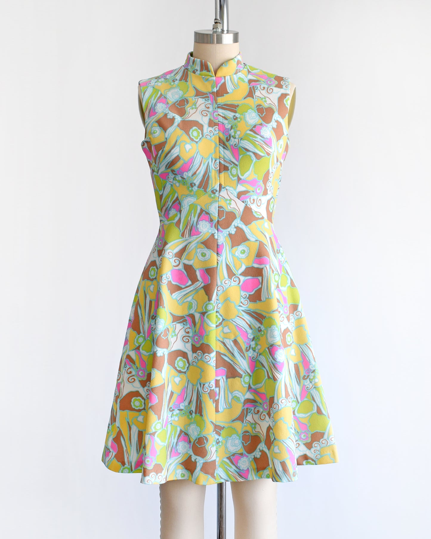 a vintage 1970s mod colorful floral dress on a mannequin against a white background