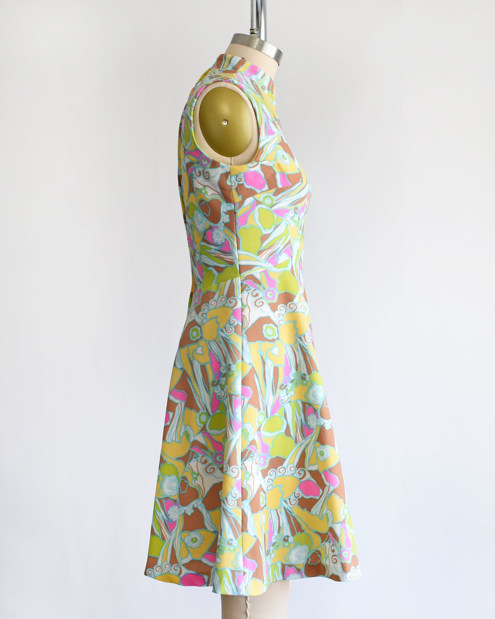 side view of a vintage 1970s mod colorful floral dress on a mannequin against a white background