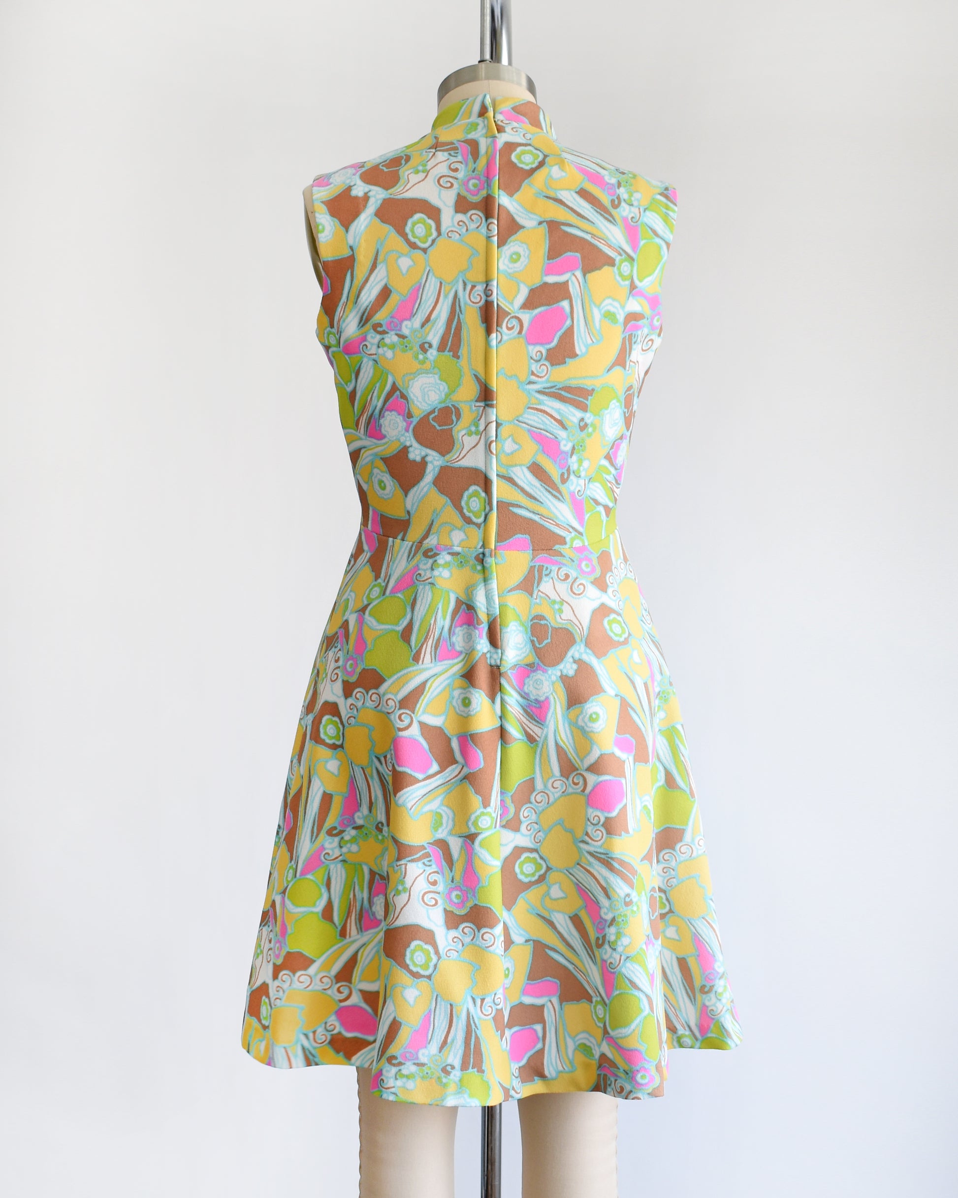 back view of a vintage 1970s mod colorful floral dress on a mannequin against a white background