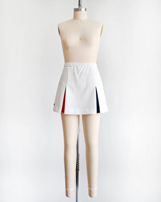 a vintage 1970s Lacoste Haymaker skirt with red and blue accented pleats on a mannequin against a white background