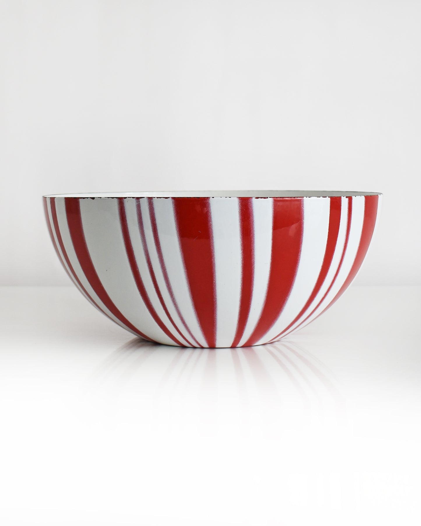 a vintage red and white striped Cathrineholm bowl on a white background