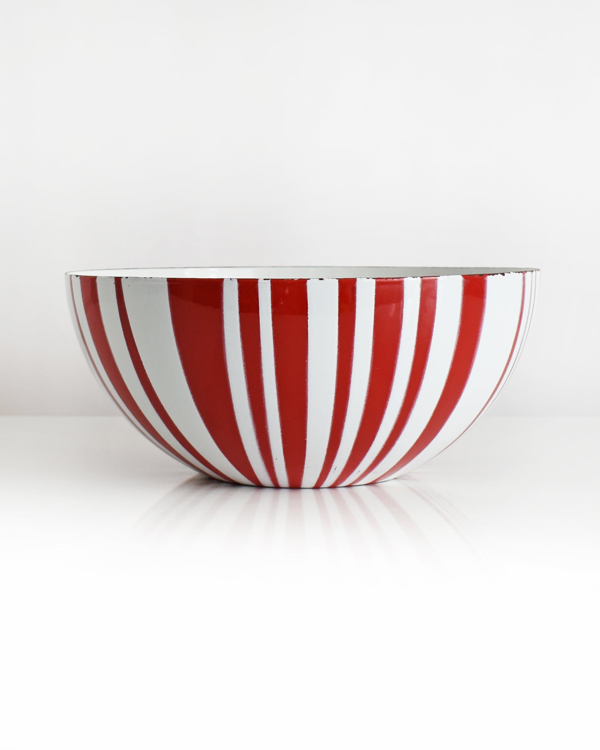 a vintage red and white striped Cathrineholm bowl on a white background