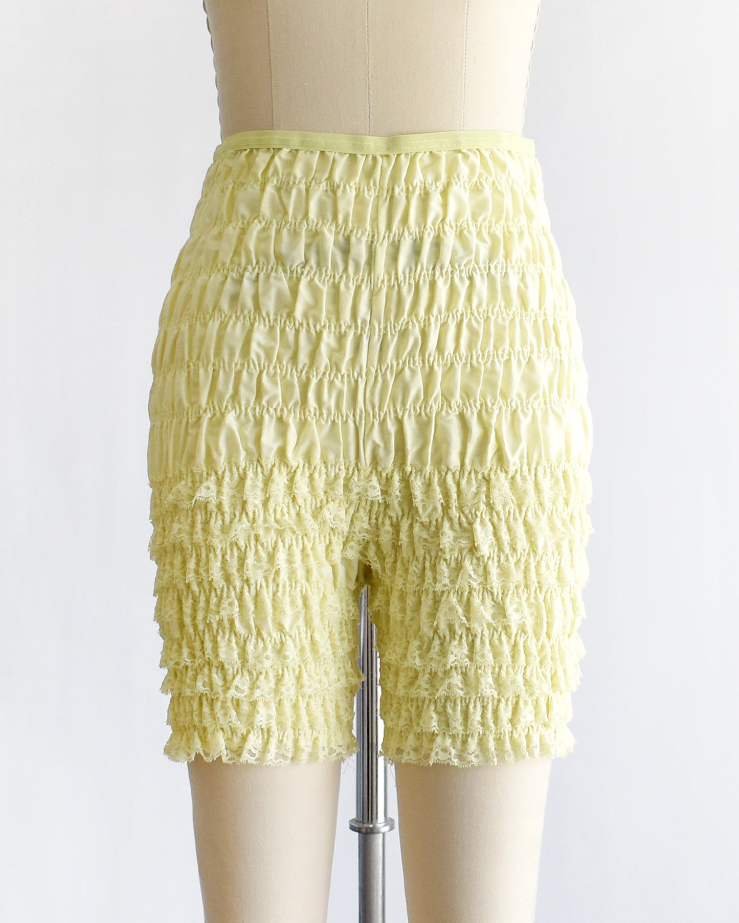 vintage yellow ruffled shorts on a mannequin against a white background