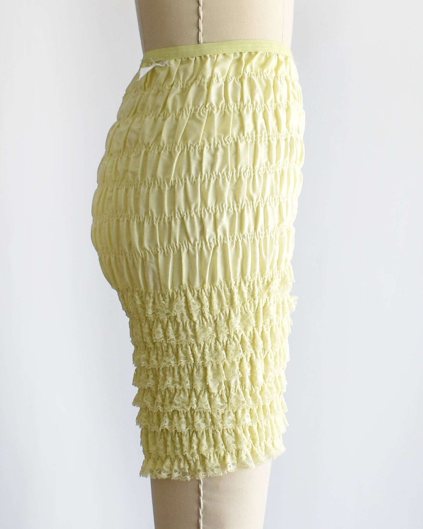 side view of vintage yellow ruffled shorts on a mannequin against a white background