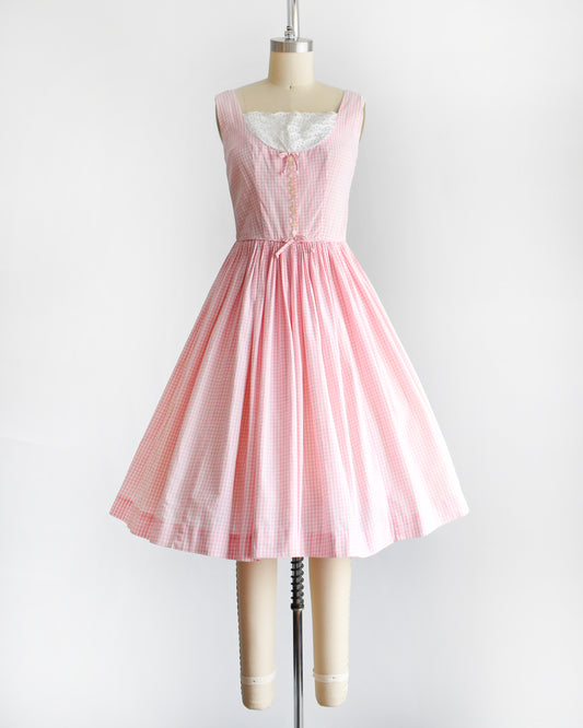 a vintage 1950s pink and white gingham dress on a mannequin against a white background