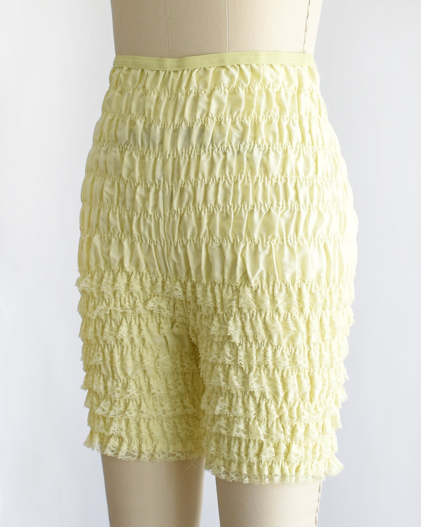 side front view of vintage yellow ruffled shorts on a mannequin against a white background